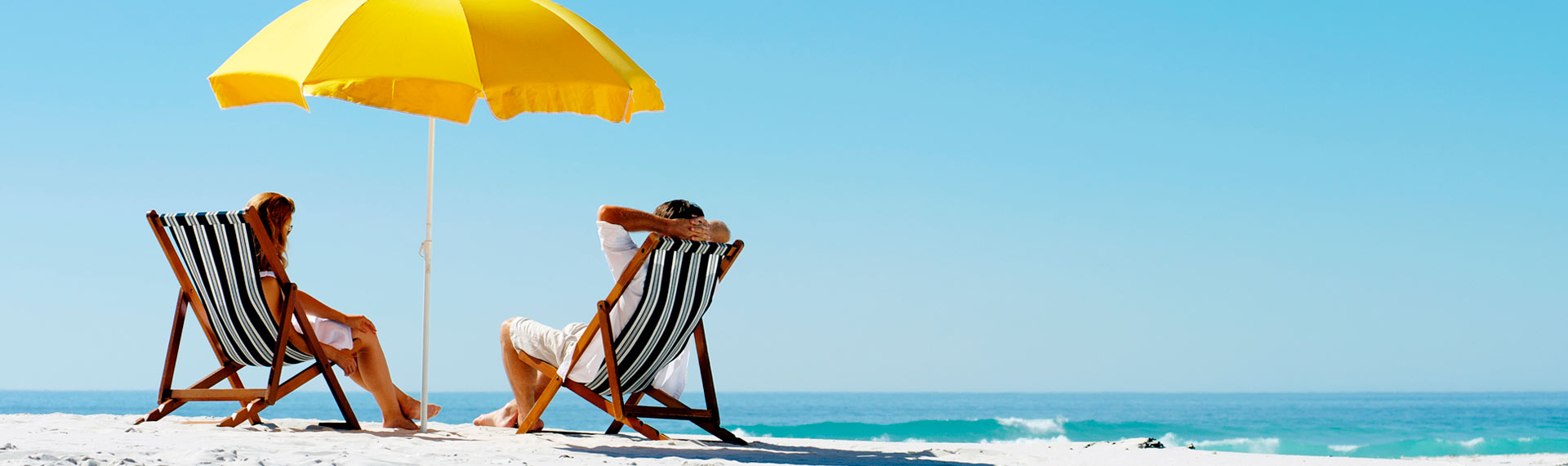 Couple sitting facing the sea on their summer holidays for the Labor day