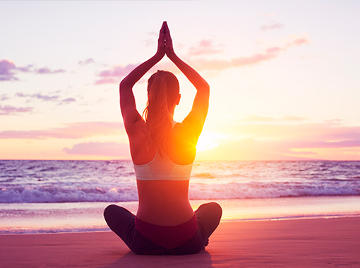 Girl practicing yoga on the beach